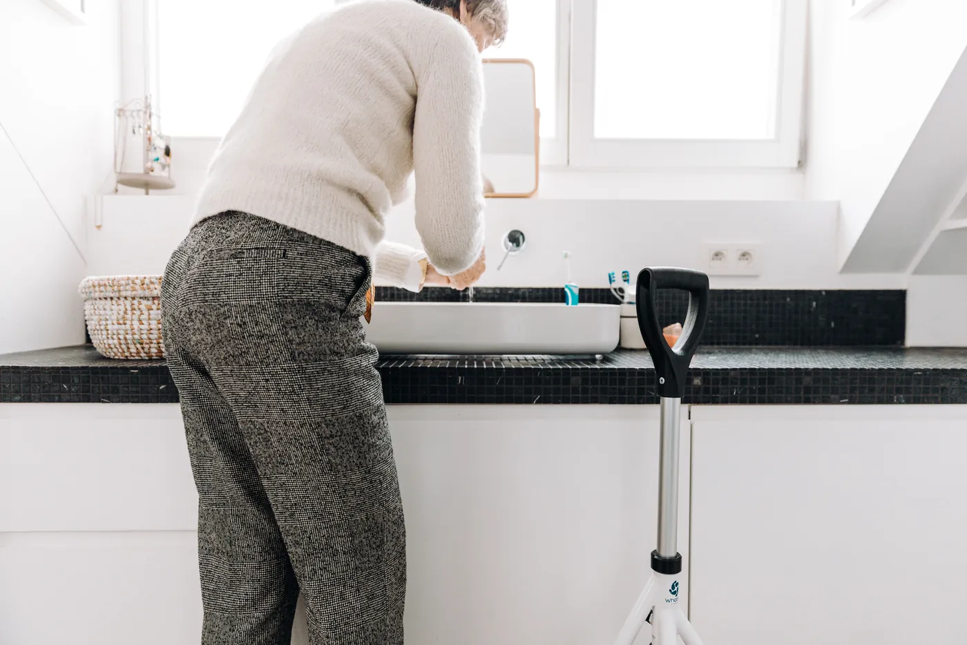 Senior se déplaçant avec une canne dans une salle de bains claire et dégagée (Rennes, Ille-et-Vilaine)
